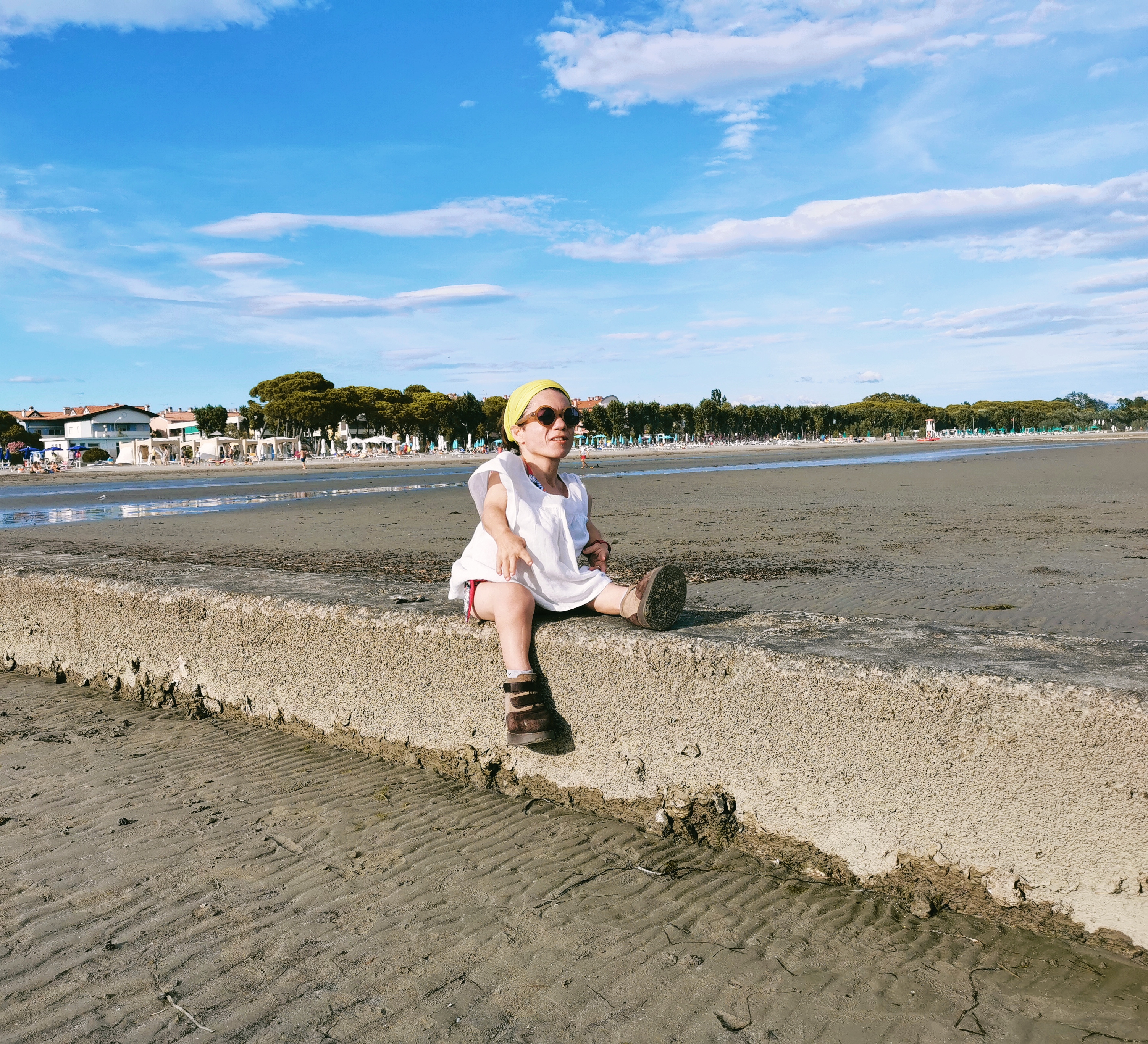 Nanabianca seduta su un muretto sulla spiaggia di Grado